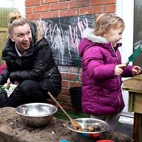 A child enjoying the outdoor nursery facilities with a staff member