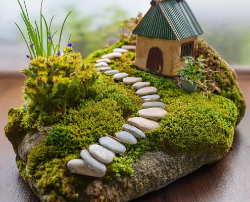 Fairy garden on a rock with pebble path and little house.