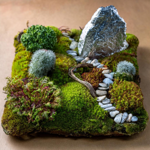 Child's fairy garden with moss, pebble path and feature rock covered in tin foil.