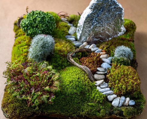 Child's fairy garden with moss, pebble path and feature rock covered in tin foil.