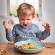 A toddler having a tantrum about his dinner.